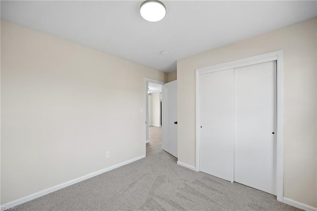 unfurnished bedroom with light carpet and a closet