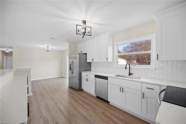 kitchen with white cabinetry, appliances with stainless steel finishes, decorative backsplash, light hardwood / wood-style flooring, and sink