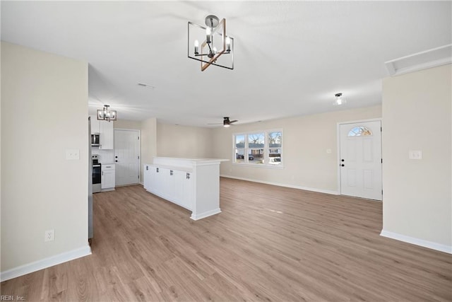 unfurnished living room featuring ceiling fan with notable chandelier and light hardwood / wood-style floors