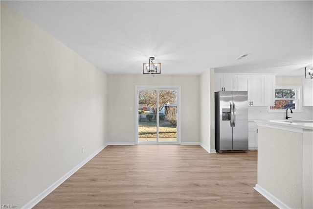 unfurnished dining area featuring sink, a chandelier, and light hardwood / wood-style floors