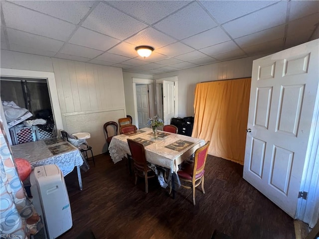 dining space with dark wood-type flooring and a drop ceiling