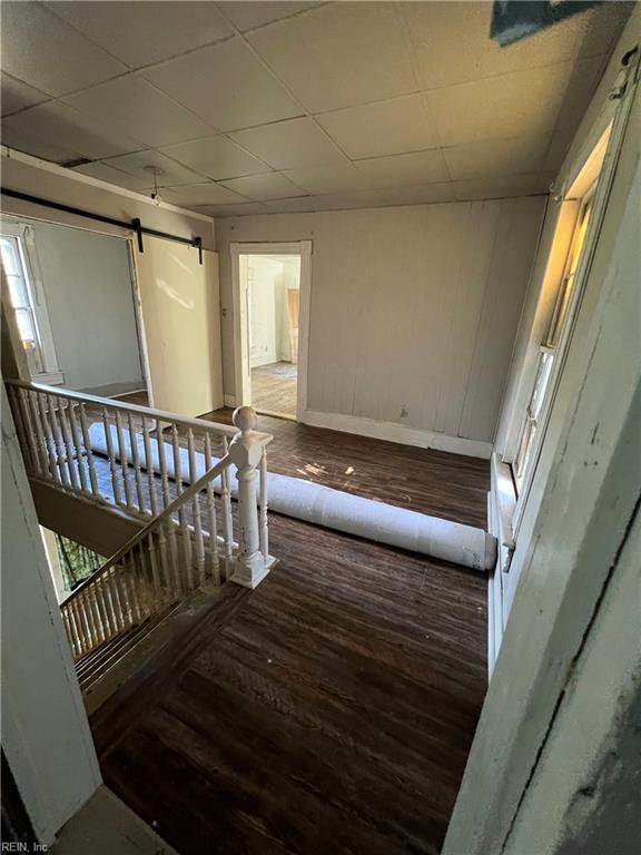 stairs featuring a paneled ceiling, a barn door, and hardwood / wood-style floors