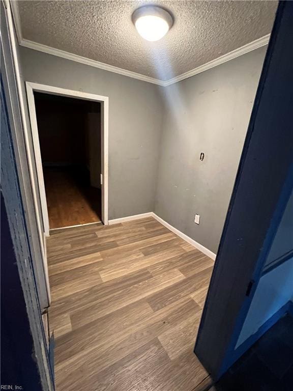 spare room featuring wood-type flooring, a textured ceiling, and ornamental molding