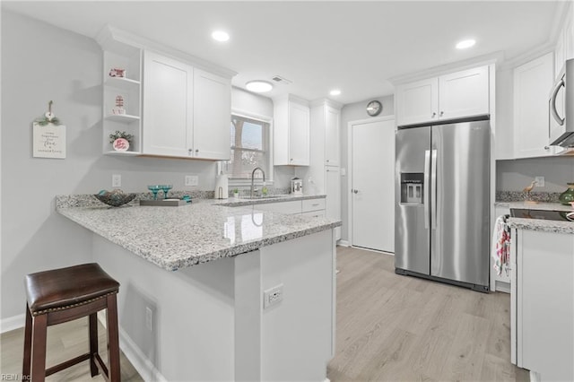 kitchen with a breakfast bar, white cabinetry, stainless steel fridge, and kitchen peninsula