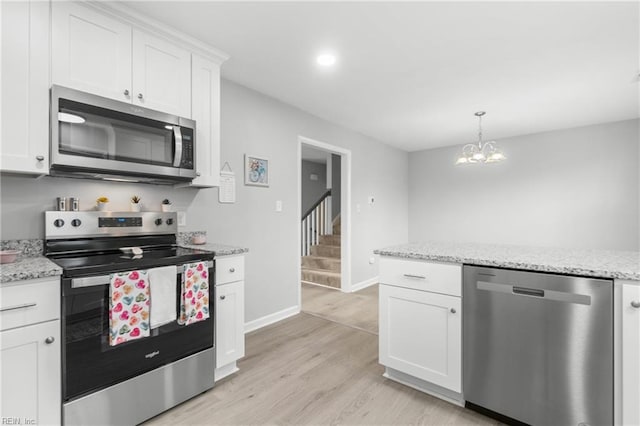 kitchen with light stone countertops, white cabinets, appliances with stainless steel finishes, and light hardwood / wood-style flooring