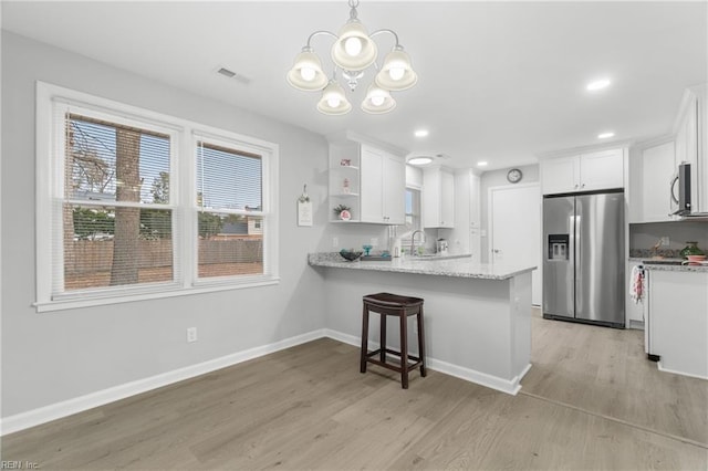 kitchen featuring white cabinetry, kitchen peninsula, stainless steel appliances, decorative light fixtures, and sink