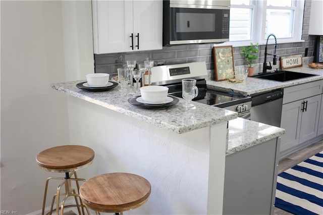 kitchen featuring a breakfast bar, appliances with stainless steel finishes, sink, and tasteful backsplash