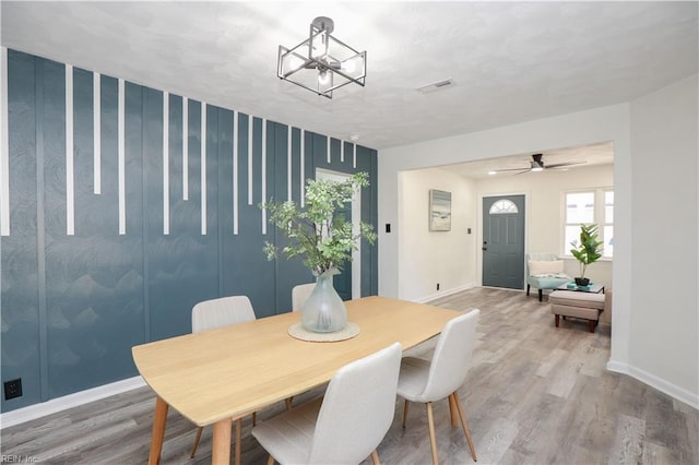 dining room featuring ceiling fan with notable chandelier and hardwood / wood-style floors