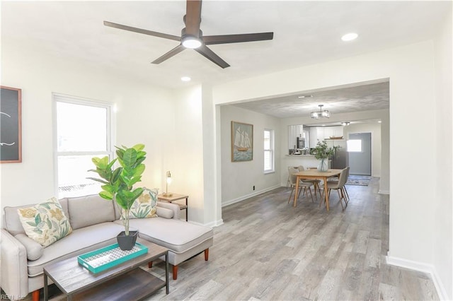 living room with ceiling fan and light hardwood / wood-style flooring