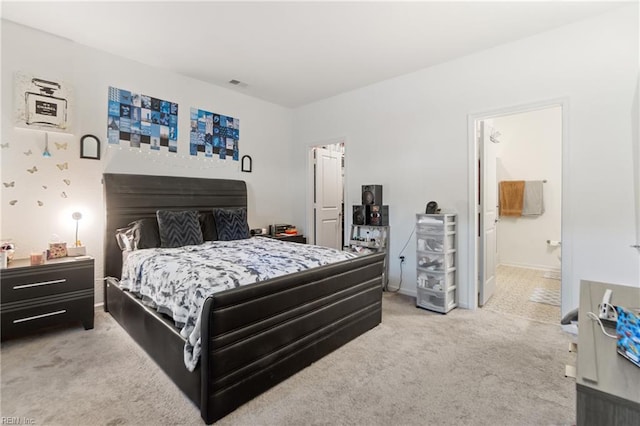 bedroom with ensuite bathroom and carpet flooring