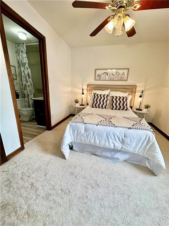 bedroom with ceiling fan, ensuite bath, and carpet flooring