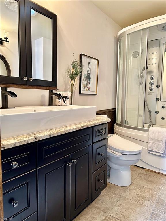 full bathroom featuring combined bath / shower with glass door, vanity, and toilet