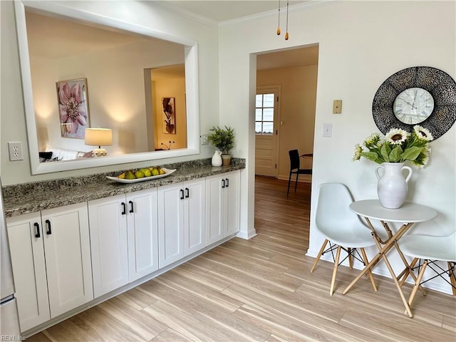 kitchen with crown molding, light wood-type flooring, stone counters, and white cabinetry