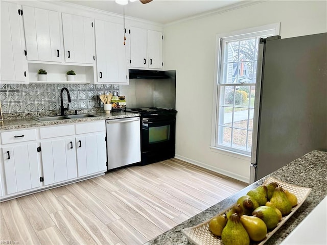 kitchen with white cabinets, appliances with stainless steel finishes, dark stone countertops, sink, and crown molding