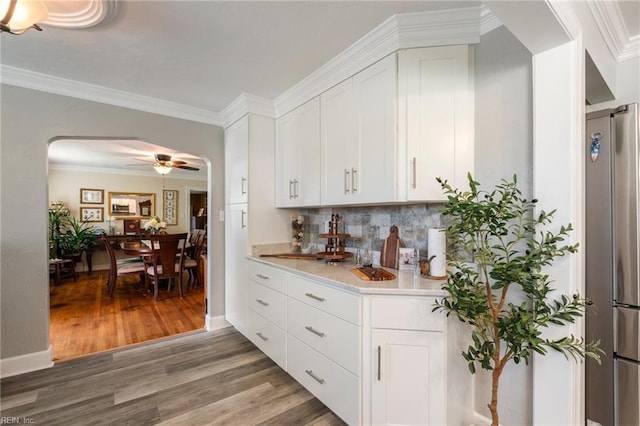 kitchen featuring stainless steel fridge, white cabinets, dark hardwood / wood-style flooring, and ornamental molding