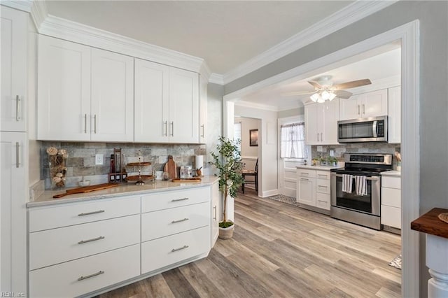 kitchen with decorative backsplash, white cabinets, and stainless steel appliances