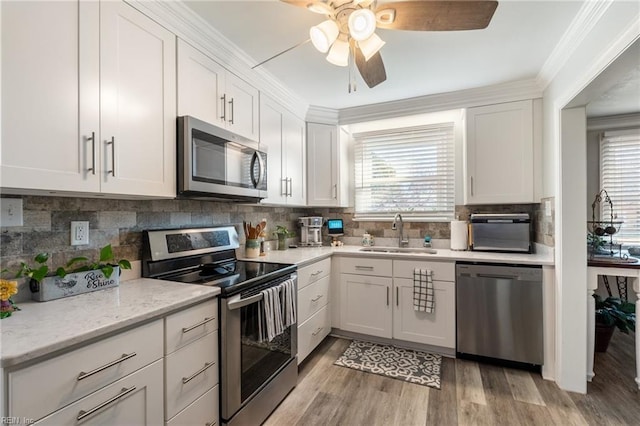 kitchen with appliances with stainless steel finishes, light hardwood / wood-style flooring, white cabinetry, and sink