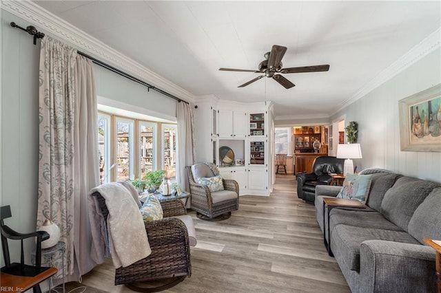 living room featuring ceiling fan, crown molding, and light hardwood / wood-style flooring