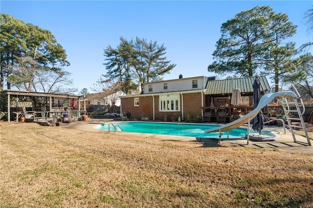 view of swimming pool featuring a lawn and a water slide