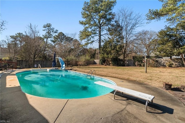 view of swimming pool featuring a yard, a water slide, a diving board, and a patio