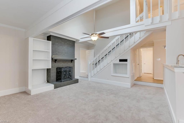 unfurnished living room with ceiling fan, light colored carpet, a fireplace, and ornamental molding