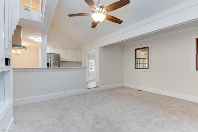 unfurnished living room with ceiling fan, light colored carpet, ornamental molding, and vaulted ceiling