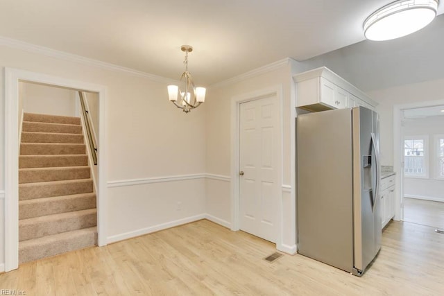 interior space with white cabinetry, stainless steel refrigerator with ice dispenser, hanging light fixtures, a chandelier, and light hardwood / wood-style flooring