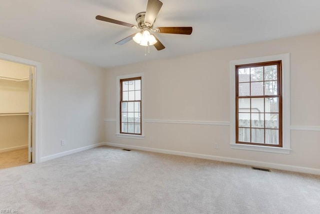 carpeted spare room with ceiling fan and plenty of natural light