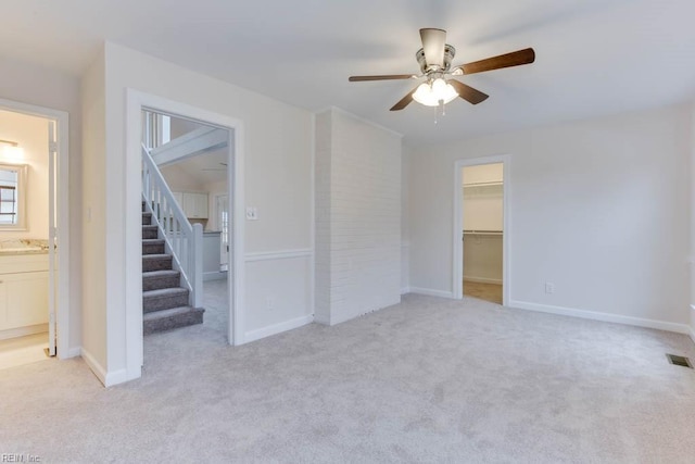 interior space with ceiling fan, connected bathroom, a closet, light colored carpet, and a walk in closet