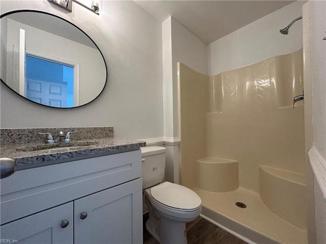 bathroom with toilet, a shower, and vanity