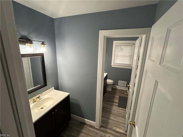 bathroom featuring toilet, vanity, and wood-type flooring