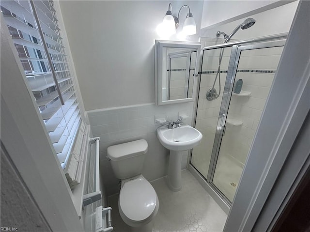 bathroom with toilet, tile patterned flooring, tile walls, and a shower with door