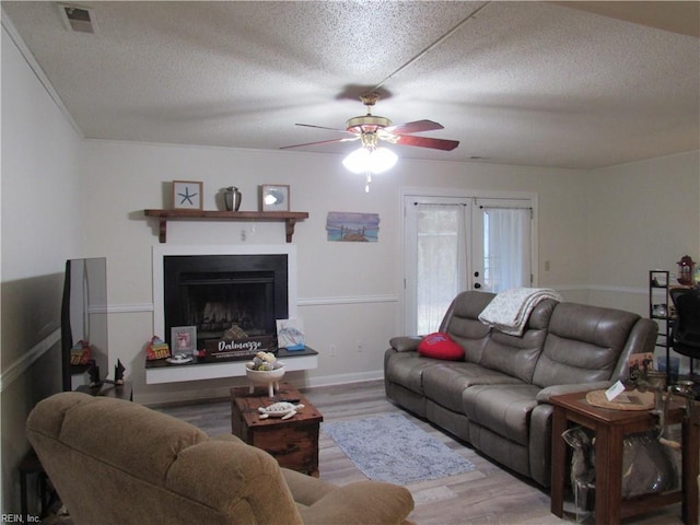 living room with a textured ceiling, ceiling fan, hardwood / wood-style flooring, and french doors