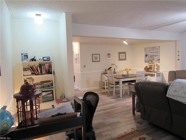 interior space with wood-type flooring, a textured ceiling, and ornamental molding