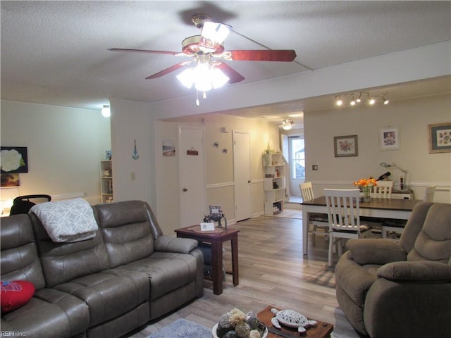 living room featuring ceiling fan, a textured ceiling, and light wood-type flooring