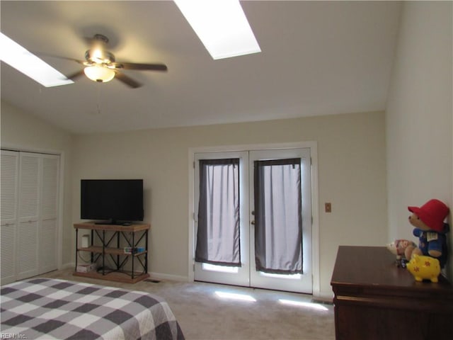 carpeted bedroom with french doors, a closet, access to outside, ceiling fan, and lofted ceiling with skylight