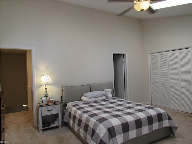 carpeted bedroom with ceiling fan, a high ceiling, and a closet