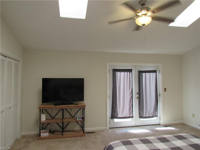 carpeted bedroom with ceiling fan, a closet, a skylight, and french doors