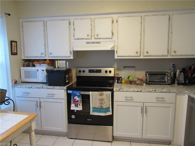 kitchen with light tile patterned floors, stainless steel appliances, and white cabinets