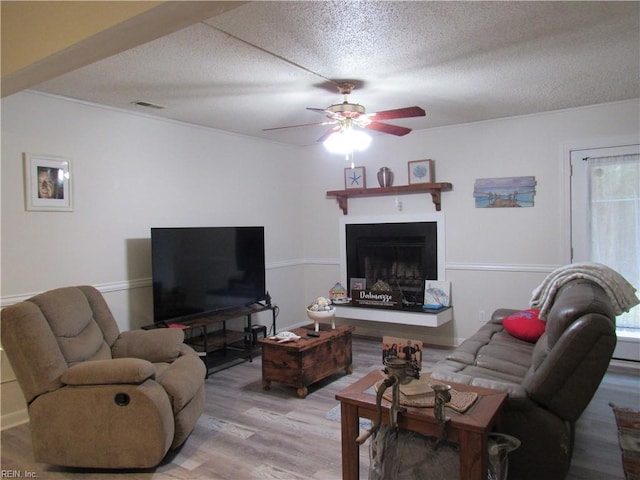 living room featuring hardwood / wood-style flooring, a textured ceiling, and ceiling fan