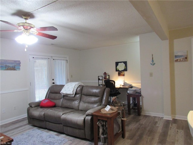 living room featuring ceiling fan, wood-type flooring, a textured ceiling, and french doors