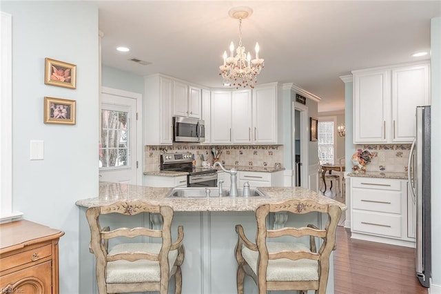 kitchen with tasteful backsplash, hanging light fixtures, white cabinetry, and stainless steel appliances