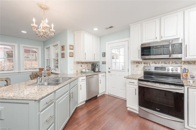 kitchen featuring sink, white cabinetry, hanging light fixtures, stainless steel appliances, and tasteful backsplash