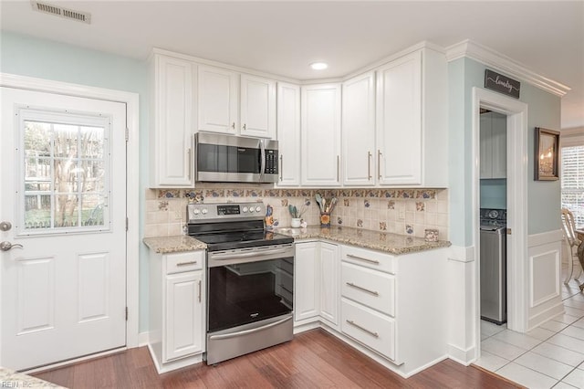 kitchen featuring tasteful backsplash, stainless steel appliances, light stone countertops, and white cabinets