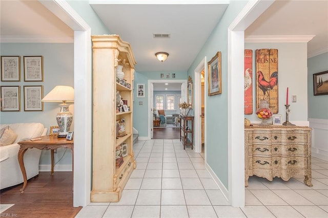 hallway with ornamental molding and light tile patterned floors