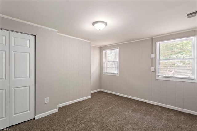 empty room with crown molding and dark carpet