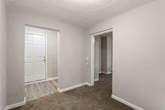 hallway featuring a textured ceiling and dark colored carpet