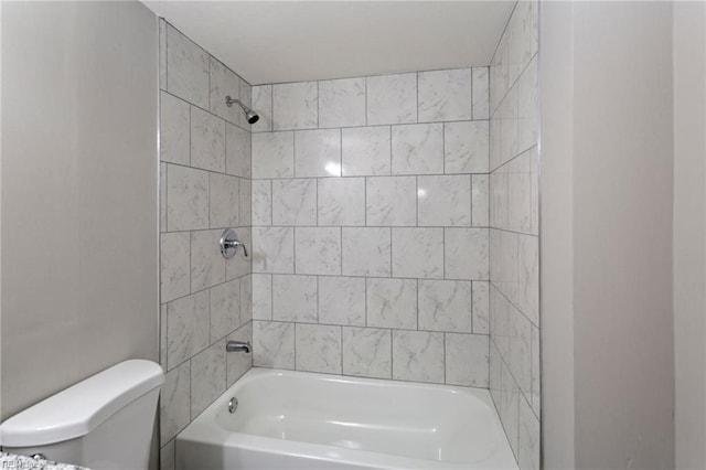 bathroom featuring toilet and tiled shower / bath