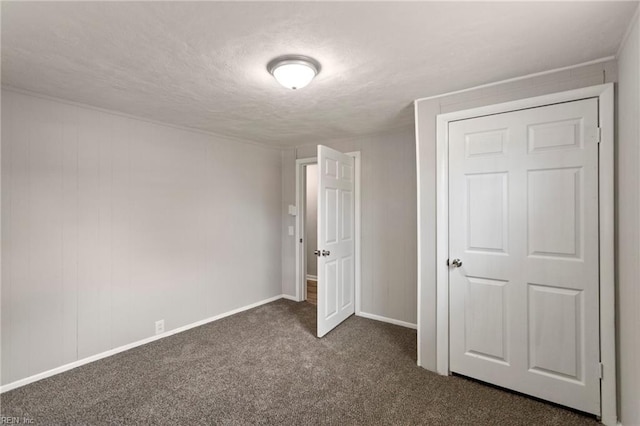 unfurnished bedroom with a textured ceiling and dark carpet