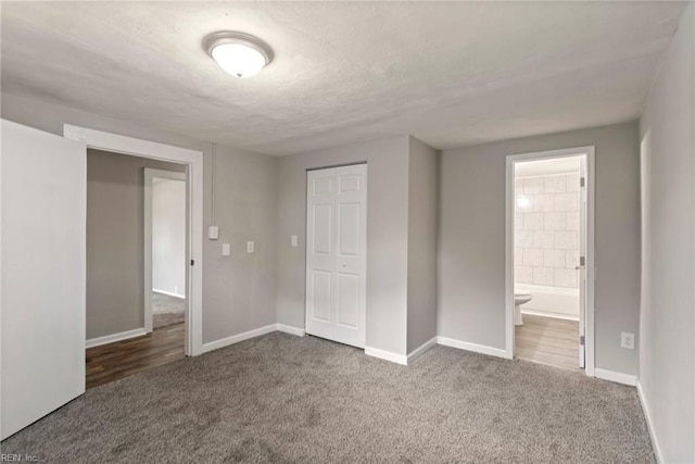 unfurnished bedroom featuring carpet floors, a closet, ensuite bath, and white fridge